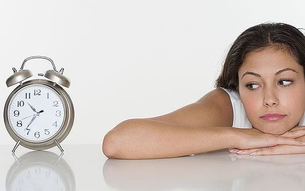 teenage girl looking at an analog clock